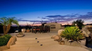 Une terrasse avec mobilier d’extérieur, un escalier en pierre et une vue sur le coucher de soleil.