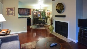 A living room with a fireplace, a television, and a dining area with chairs and a table. - Traditional Touch By Signature Vacation Rentals (Scottsdale)