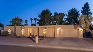 A two-story house with a garage, arched windows, and a well-maintained lawn. - Thunderbird By Signature Vacation Rentals (Scottsdale)