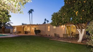A two-story house with a well-maintained lawn, outdoor seating area, and a pool. - Thunderbird By Signature Vacation Rentals (Scottsdale)