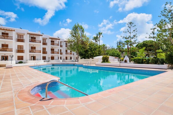 A swimming pool with a tiled deck, surrounded by a multi-story building with balconies. - Azuline Apartamentos Can Sanso (Santa Eulalia del Rio)