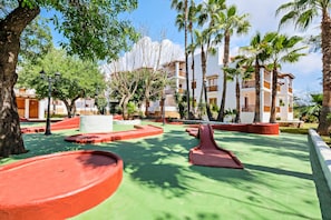 A resort courtyard with palm trees, a pool, and a building with balconies. - Azuline Apartamentos Can Sanso (Santa Eulalia del Rio)