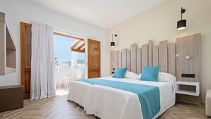 Un dormitorio con una cama grande, cabecera de madera, mesita de noche blanca y vistas al exterior.