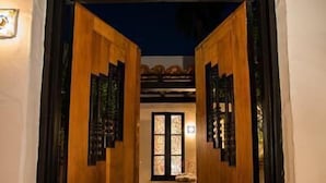 A pathway leading to a building entrance with wooden doors and a tiled floor.