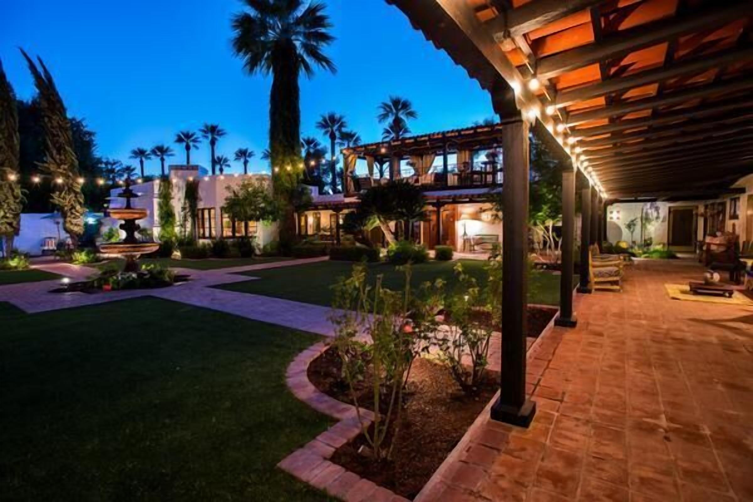 A well-lit outdoor area with a fountain, palm trees, and a covered patio.