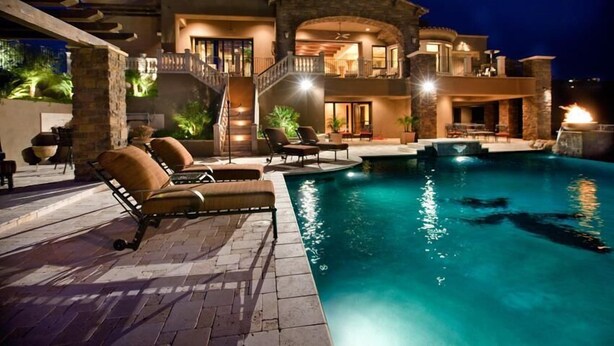 A large, two-story house with a swimming pool, outdoor seating, and a well-lit patio area. - Bella Estate By Signature Vacation Rentals (Scottsdale)
