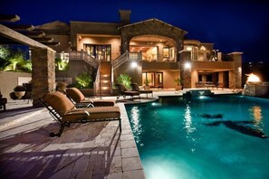A large, two-story house with a swimming pool, outdoor seating, and a well-lit patio area. - Bella Estate By Signature Vacation Rentals (Scottsdale)