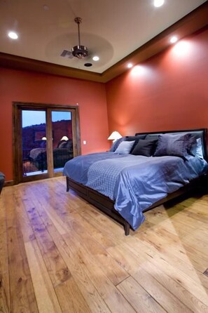 A bedroom with a bed, a ceiling fan, and a view through a glass door.
