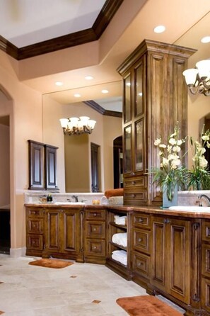 A bathroom with a large wooden vanity, a mirror, and a potted orchid plant.