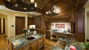 A spacious kitchen with a central island, wooden cabinetry, and a stone countertop. - Bella Estate By Signature Vacation Rentals (Scottsdale)