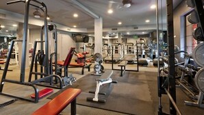 Une salle de sport équipée de divers appareils d’exercice, notamment des tapis de course, des appareils de musculation et des bancs.