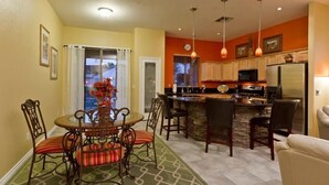 A modern kitchen with a central island, bar stools, and pendant lighting. - Augusta On The Green by Signature Vacation Rentals (Mesa)