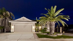A residential house with a garage, a well-maintained lawn, and a palm tree. - Augusta On The Green by Signature Vacation Rentals (Mesa)