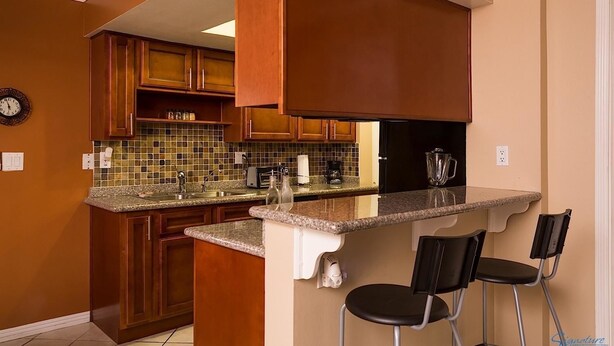 A kitchen with wooden cabinets, a granite countertop, a built-in oven, and a coffee maker. - Arizona Grande By Signature Vacation Rentals (Phoenix)