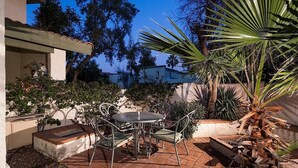 A patio with a round table and chairs, surrounded by plants and a brick floor. - Arizona Grande By Signature Vacation Rentals (Phoenix)