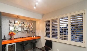 A kitchen with a bar area, a refrigerator, and a window with blinds. - Amour By Signature Vacation Rentals (Scottsdale)