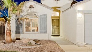 A white building with a large arched window, a palm tree, and a gravel driveway. - All Star By Signature Vacation Rentals (Chandler)