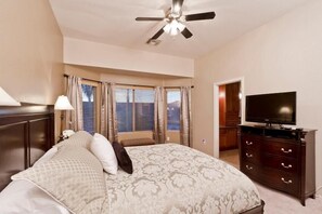 A bedroom with a bed, a dresser, a television, and a ceiling fan. - All Star By Signature Vacation Rentals (Chandler)