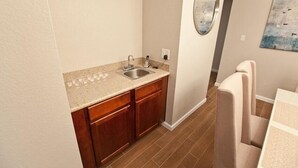 A compact kitchen with a sink, wooden cabinets, and a countertop. - Admirals House By Signature Vacation Rentals (Scottsdale)