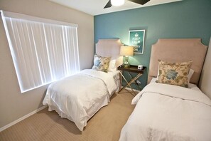 A hotel room with two beds, a nightstand, a lamp, and a wall with a 'KEEP CALM AND CARRY ON' sign. - Admirals House By Signature Vacation Rentals (Scottsdale)