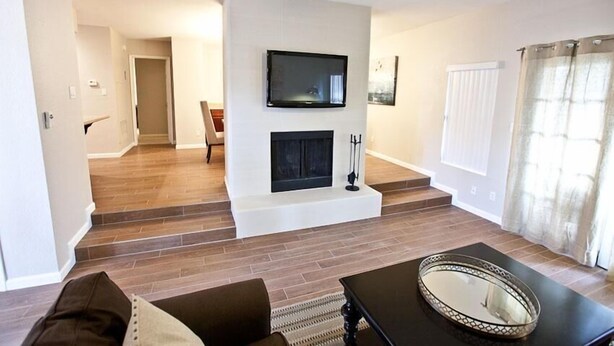 A living room with a fireplace, a television mounted above it, and a ceiling fan. - Admirals House By Signature Vacation Rentals (Scottsdale)