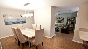 A dining area with a table and chairs, a chandelier, and a painting on the wall. - Admirals House By Signature Vacation Rentals (Scottsdale)