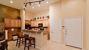 A kitchen with wooden cabinets, a microwave, and a white door. - Acacia Loft By Signature Vacation Rentals (Cave Creek)