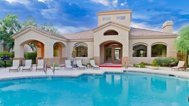 A large house with a swimming pool, multiple arches, and a red carpet leading to the entrance. - Acacia Loft By Signature Vacation Rentals (Cave Creek)