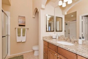 A bathroom with a large sink, wooden cabinets, a mirror, and a towel rack with towels.