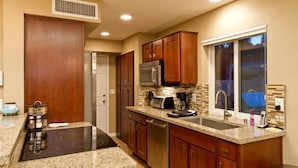 A modern kitchen with granite countertops, stainless steel appliances, and wooden cabinets. - 19th Hole By Signature Vacation Rentals (Phoenix)
