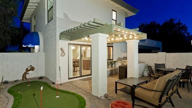 A modern house with a patio area featuring outdoor furniture and a small putting green. - 19th Hole By Signature Vacation Rentals (Phoenix)
