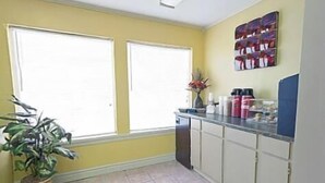 A kitchen with two windows, a potted plant, and a countertop with kitchen items. - Kinder Inn (Kinder)