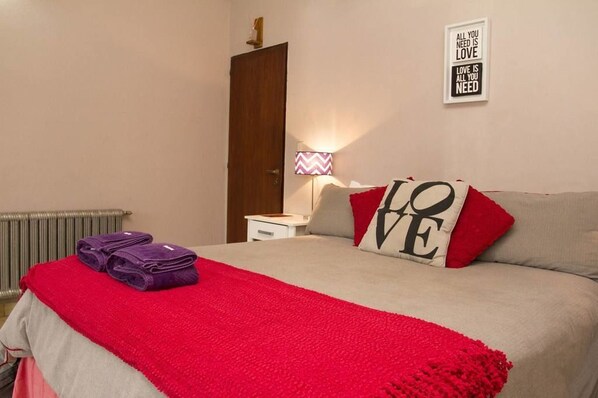 A neatly made bed with a red blanket, a pillow with "LOVE" on it, and a wall with a motivational quote. - Posada del Centro (Villa General Belgrano)