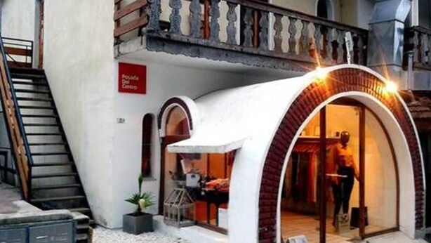 Un hotel boutique con una entrada en arco, una escalera que conduce a un piso superior y un letrero que indica un restaurante en la planta baja.