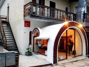 A boutique hotel with an arched entrance, a staircase leading to an upper floor, and a sign indicating a restaurant on the ground floor. - Posada del Centro (Villa General Belgrano)