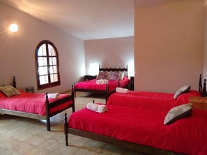 A room with three wooden beds, each with a red bedspread and white pillows. - Posada del Centro (Villa General Belgrano)