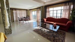 A spacious living room with a red sofa, a glass coffee table, and a dining area with a table and chairs. - Punta De Fabian (Baras)