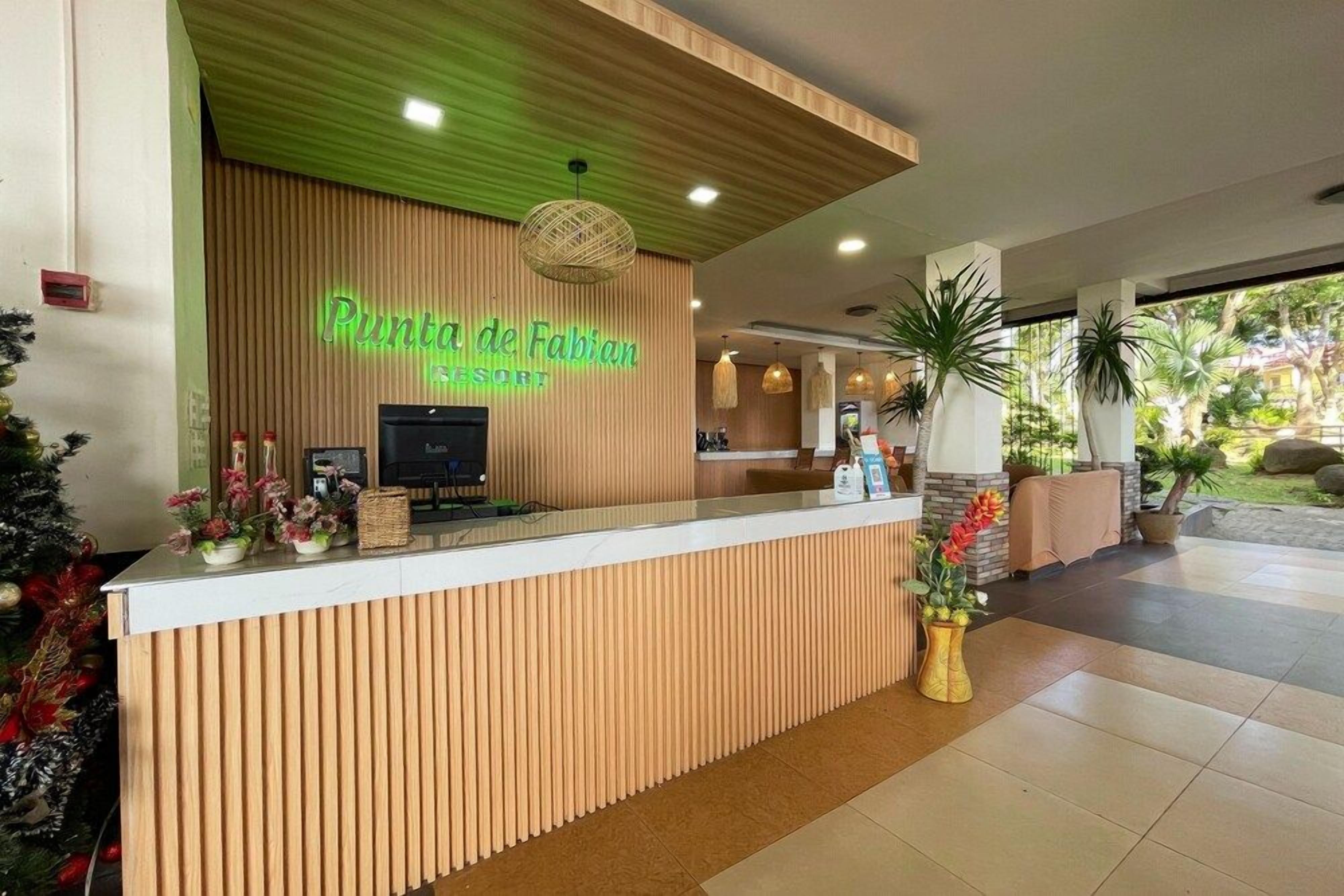 A reception desk at Puntura de Fabian Resort with a wooden panel design, a neon sign, and a reception area with a counter and chairs.
