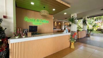 A reception desk at Puntura de Fabian Resort with a wooden panel design, a neon sign, and a reception area with a counter and chairs.