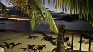 A beach with lounge chairs and a palm tree. - TW Guaimbê Exclusive Suites (Ilhabela)