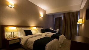 A hotel room with two beds, bedside lamps, a desk, and a chair. - Hotel Costé (Tbilisi)