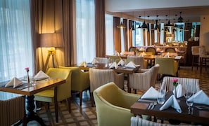 Un restaurant avec plusieurs tables et chaises, certaines étant équipées de serviettes et de couverts.
