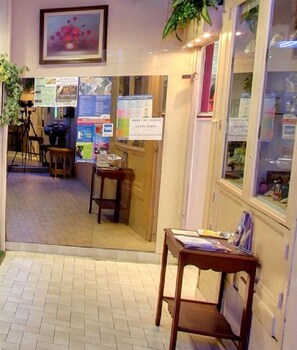 Un pasillo con suelo de baldosas, muebles de madera y carteles informativos en las paredes.