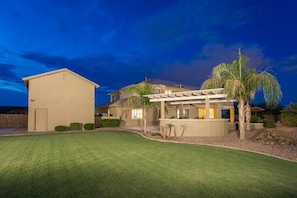 A two-story house with a covered patio and a well-maintained lawn.