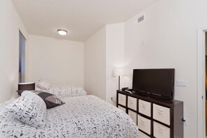 A bedroom with a bed, a TV, a lamp, and a dresser. - The Place To Be By Signature Vacation Rentals (Phoenix)