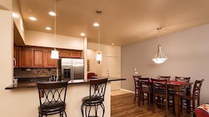 A modern kitchen with wooden cabinets, a stainless steel refrigerator, and pendant lighting. - The Keep at La Verne By Signature Vacation Rentals (Phoenix)