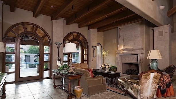 A spacious living room with high ceilings, a fireplace, and large windows. - The Keep at La Verne By Signature Vacation Rentals (Phoenix)