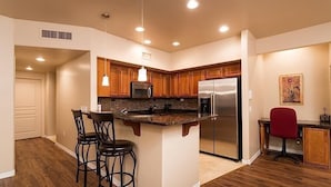 A modern kitchen with wooden cabinets, a stainless steel refrigerator, and a granite countertop. - The Keep at La Verne By Signature Vacation Rentals (Phoenix)
