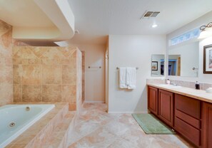 A modern bathroom with a bathtub, shower, and vanity.