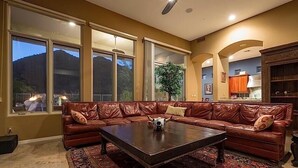 Amplia sala de estar con un sofá modular grande, una mesita de centro y grandes ventanales que ofrecen vistas al exterior.